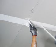 A male hand working on a drywall ceiling